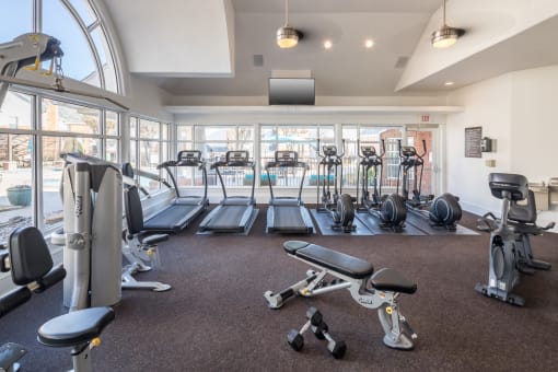 A gym with a variety of equipment including treadmills, weights, and exercise machines at McDermott Place, Plano, Texas