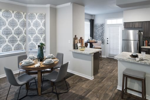 Dining Area with Wood-Style Flooring, Table, Chairs, Granite Countertops, View of Kitchen, and Nine-Foot Ceilings with Crown Molding at McDermott Place, Texas