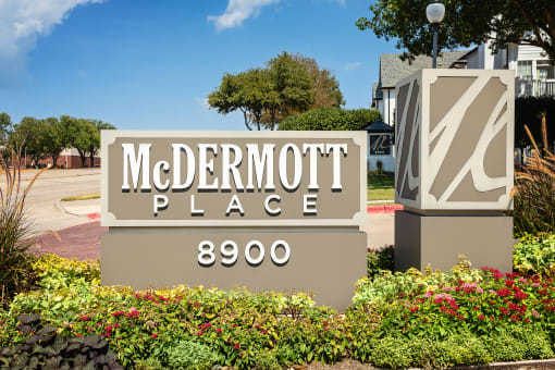 Apartment For Rent In Plano, TX - McDermott Place - Front Welcome Sign Of McDermott Place With Lush Green Landscaping And Street View