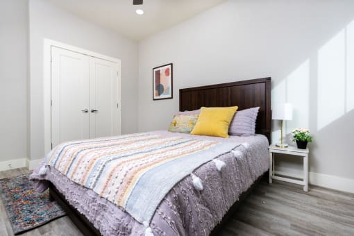 mihir taylor model bedroom with white walls and a bed with colorful pillows