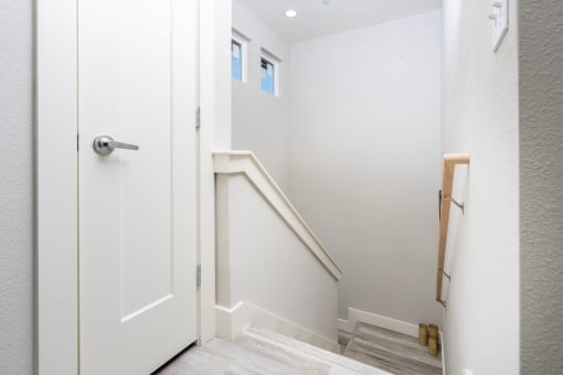 the landing of a staircase in a home with white walls and a door