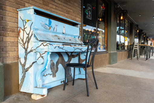 a piano outside of a restaurant with a chair