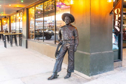 a statue of a man in a cowboy hat standing on a sidewalk