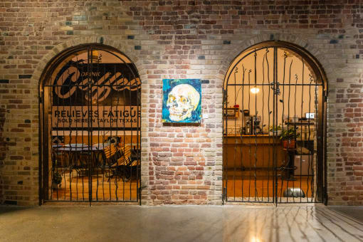 two arched doors with a bar and a sign on a brick wall