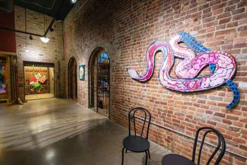a large snake artwork on a brick wall in a room with chairs