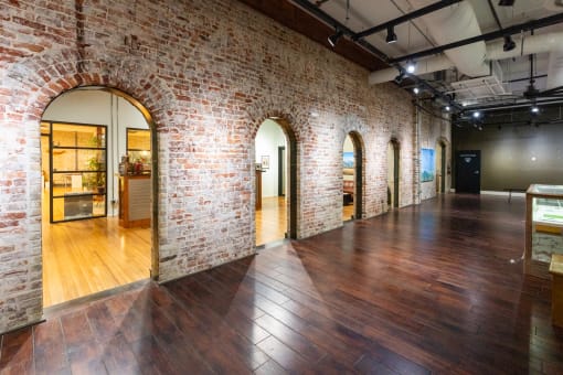 a large room with wood floors and brick walls and arched doorways