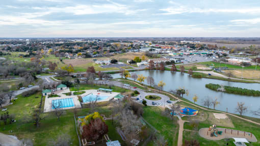 an aerial view of a park with a lake and a city in the background