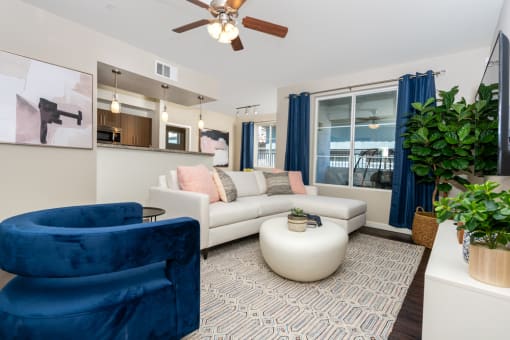 a living room with a white couch and blue chairs and a ceiling fan at Miro at the Parc, Nevada