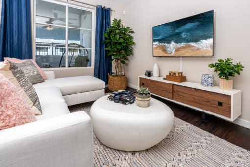 a living room with a white couch and a coffee table and a television at Miro at the Parc, Henderson, NV