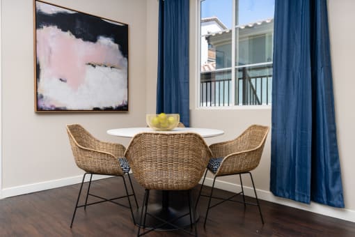 a dining area with a table and chairs and a window with blue curtains at Miro at the Parc, Henderson, 89074