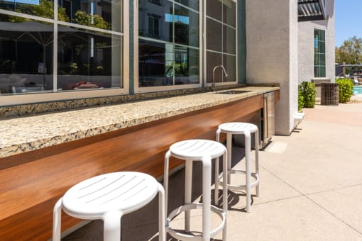 a bar with three white stools in front of a window at Miro at the Parc, Henderson, 89074