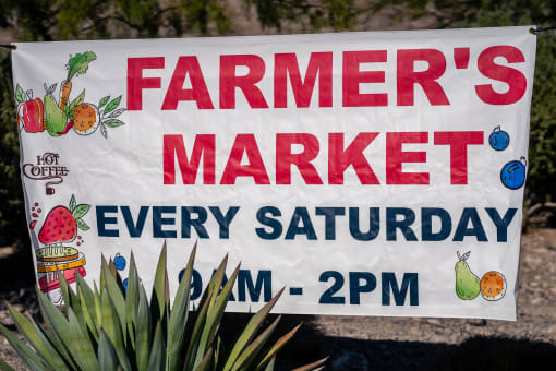a farmers market sign is displayed in front of a plant at Miro at the Parc, Henderson, NV 89074