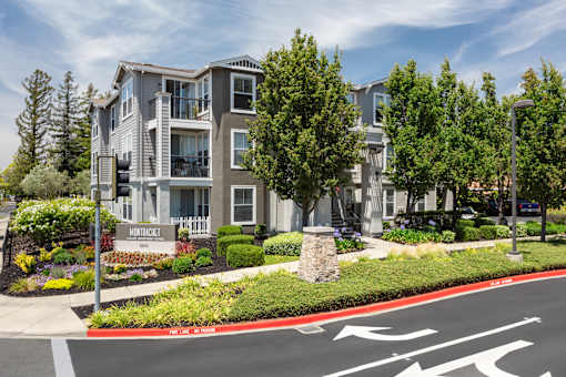 A street view of Monrovia apartments with a red curb and a crosswalk.