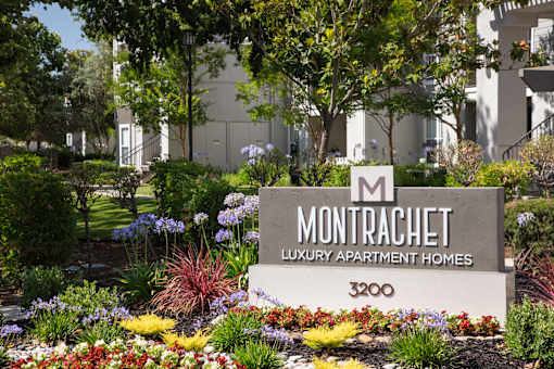 A sign for Montrachet Luxury Apartment Homes stands in front of a building.