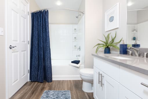 a bathroom with white cabinets and a blue shower curtain at Montrachet Apartments, Napa, CA