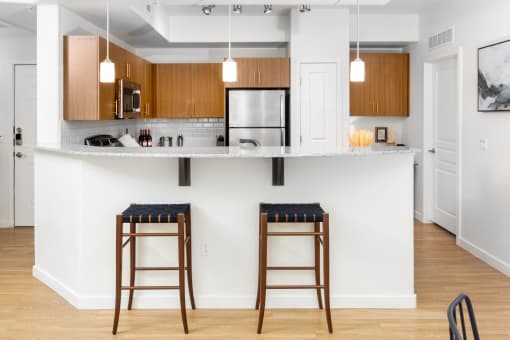 a kitchen with two bar stools in front of a counter top at Monument, Chandler, AZ