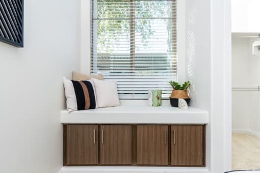 a window seat with a few pillows and a plant