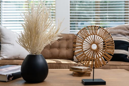 a living room with a table with a vase of wheat on it