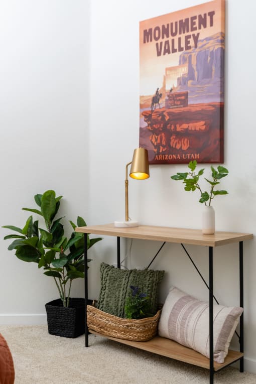 a console table with a lamp and plants in a living room