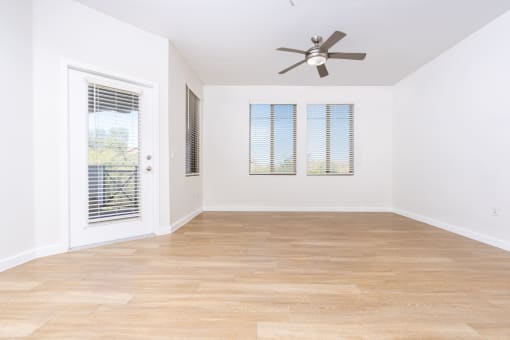 an empty living room with a ceiling fan and a window