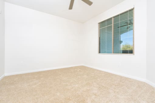 an empty room with a window and a ceiling fan