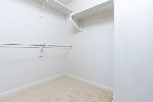 a empty room with a white wall and a hanging rail in a closet