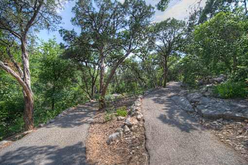 A winding path through a wooded area with rocks on the side.