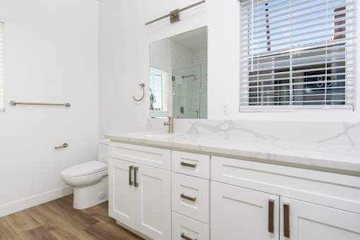 A white bathroom with a toilet, sink, and mirror. at Nola 624, California, 91790