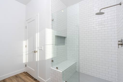 A white tiled bathroom with a walk-in shower. at Nola 624, West Covina California