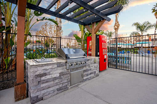 A barbecue grill is set up on a patio with a pool in the background. at Nola 624, West Covina, 91790  