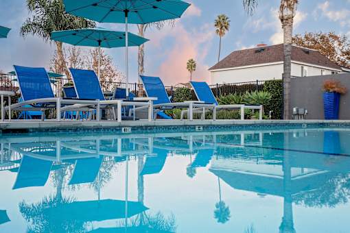 A pool with blue lounge chairs and umbrellas. at Nola 624, California, 91790