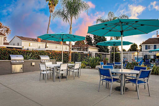 A patio with a table and chairs under a blue umbrella. at Nola 624, West Covina California