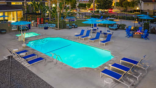 A large swimming pool surrounded by blue lounge chairs and umbrellas. at Nola 624, West Covina California