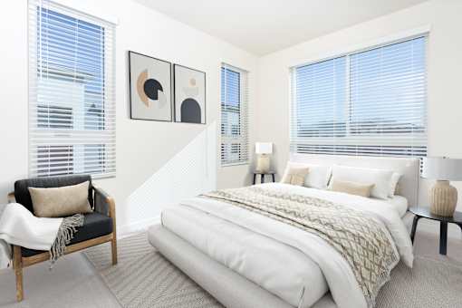 A bedroom with a large bed and a chair.