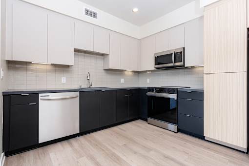A kitchen with black and white cabinets and a microwave above the stove.