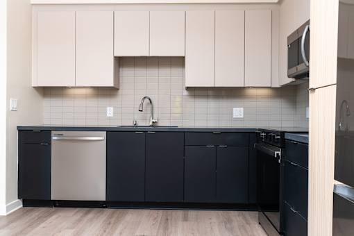 A kitchen with black cabinets and a white dishwasher.