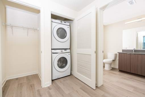 A white washer and dryer are stacked in a small laundry room.