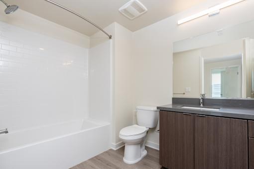 A white toilet sits next to a white bathtub in a bathroom.