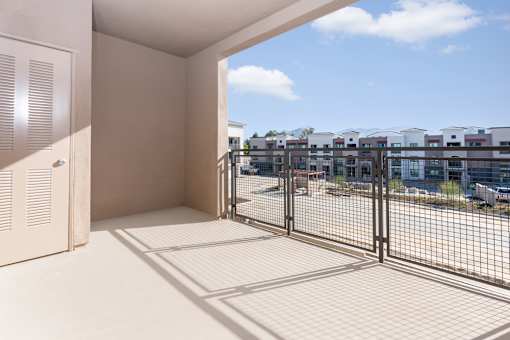 A balcony with a view of a parking lot and buildings.