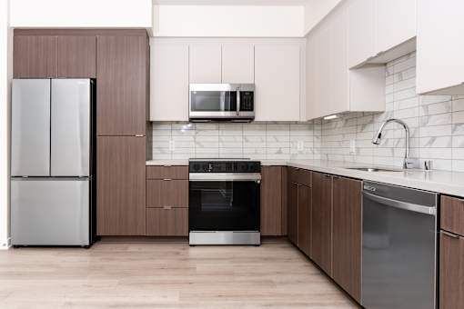 A modern kitchen with a refrigerator, oven, microwave, and sink.