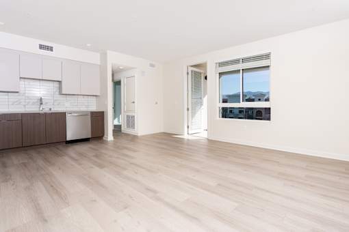 A spacious room with wooden flooring and a view of buildings outside the window.