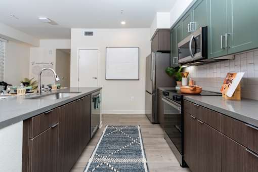 Riverside, CA Luxury Apartments with In-Unit Washer and Dryer - North Grove - Modern Kitchen With Two Tone Cabinets, Stainless Steel Appliances, Center Island Sink, And Sleek Pendant Lighting