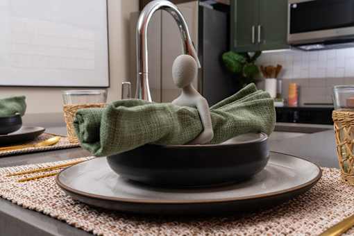 A Small Green Towel Wrapped Around a Grey Bowl Sits On a Plate at North Grove, Riverside, CA