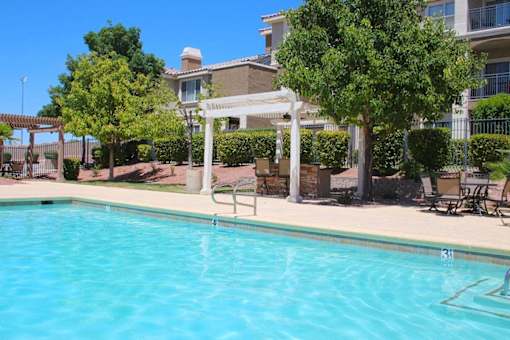 A pool with a white pergola and trees in the background at Avalon at Seven Hills Apartments, Henderson, NV, 91790