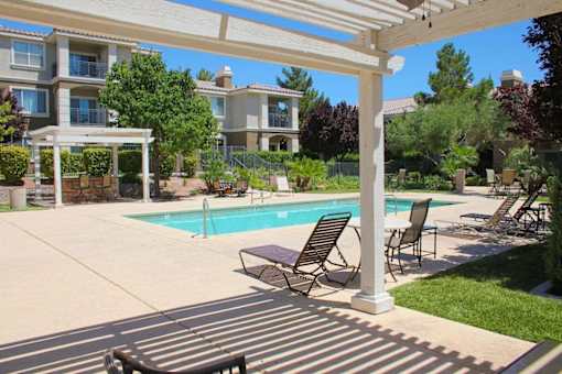 A pool surrounded by chairs and a white pergola at Avalon at Seven Hills Apartments, Nevada, 91790