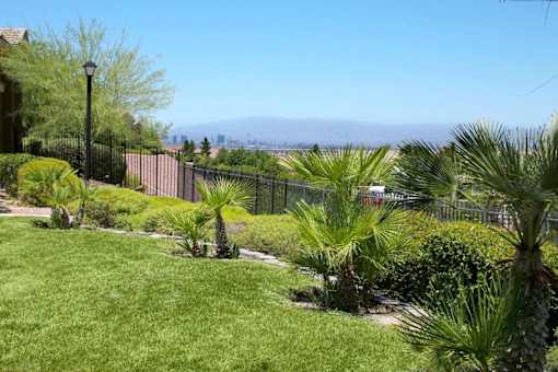 A green lawn with a black fence and palm trees at Avalon at Seven Hills Apartments, Henderson, 91790