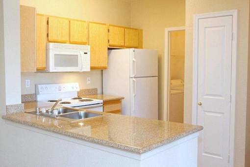 A kitchen with a white fridge and microwave above the stove at Avalon at Seven Hills Apartments, Henderson, NV, 91790