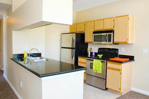 A kitchen with a black counter top and stainless steel appliances at Avalon at Seven Hills Apartments, Nevada