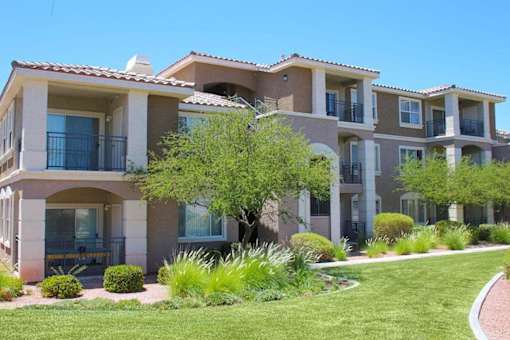 A row of houses with balconies and a green lawn in front.