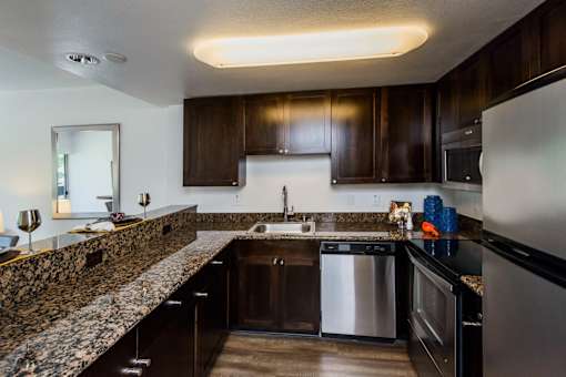 A kitchen with dark wood cabinets and granite countertops.